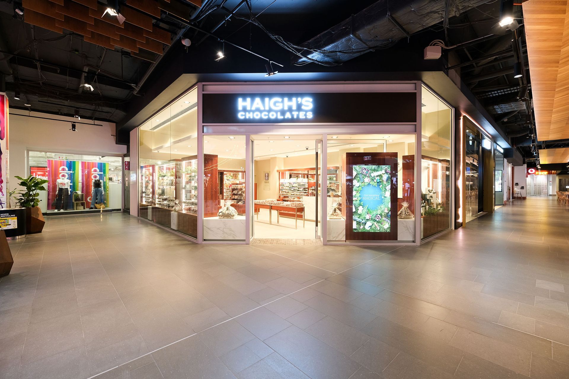 Haigh's Chocolates storefront in a mall, with glass windows displaying products. Brown and white exterior.