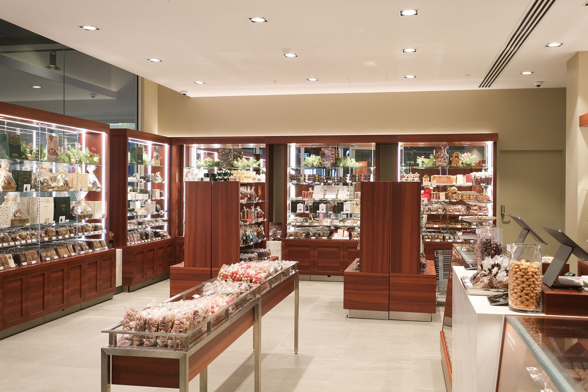 Inside a chocolate shop, wood shelves with displays. Various treats and products are visible.