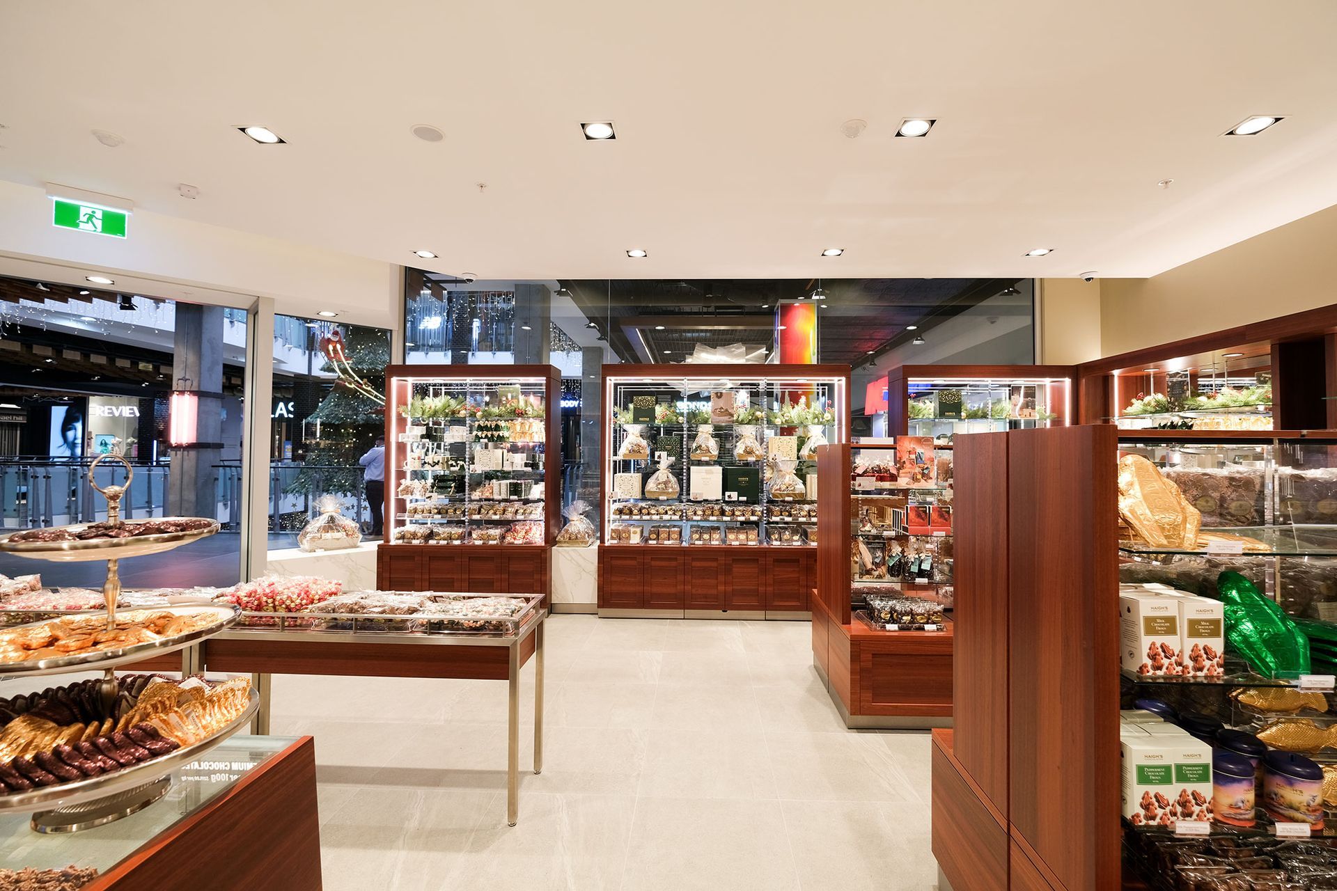 Interior of a chocolate shop with glass display cases, wood fixtures, and treats on tables.