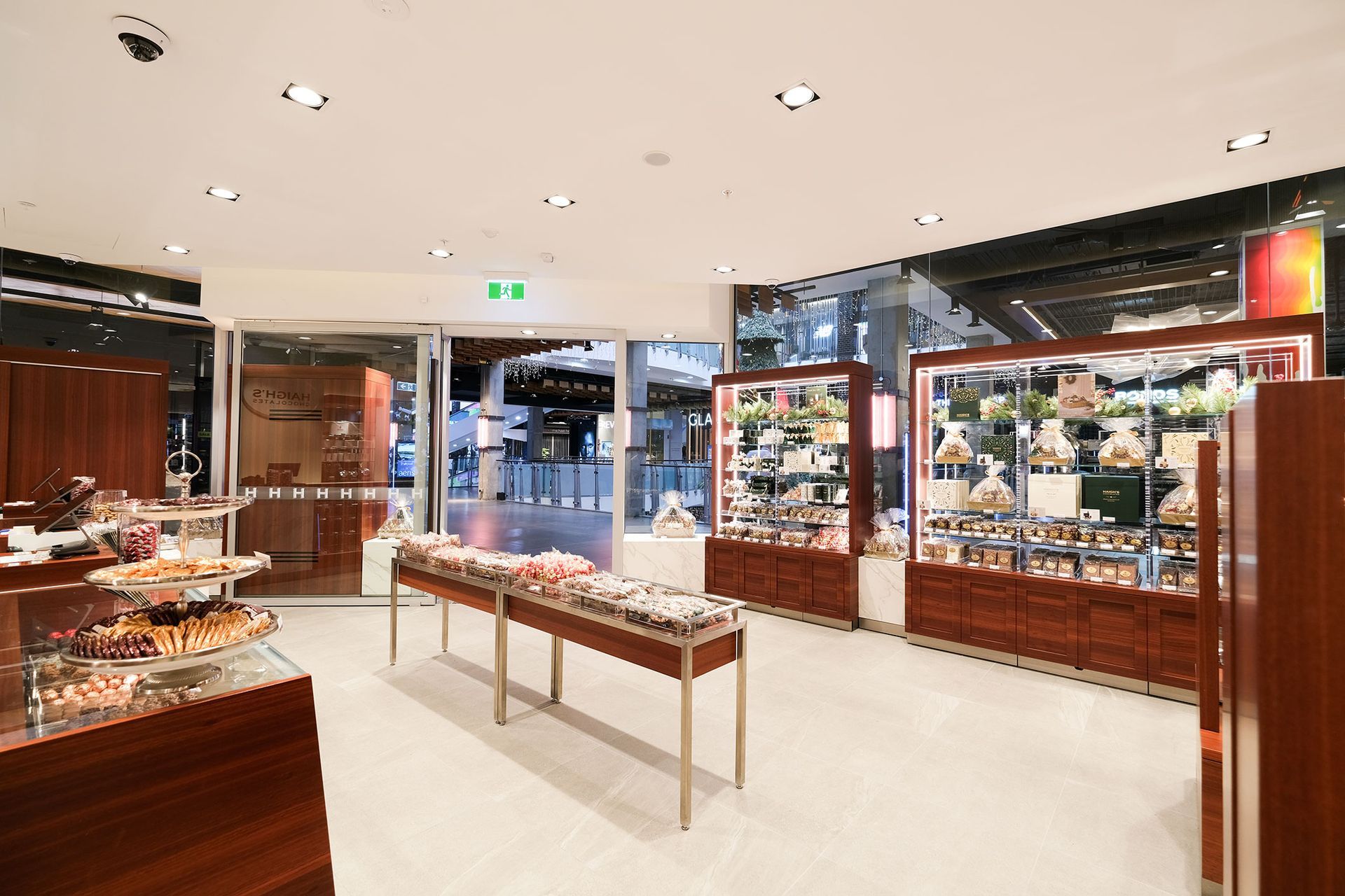 Interior view of a well-lit retail store with display cases of merchandise and open entrance to a public space.