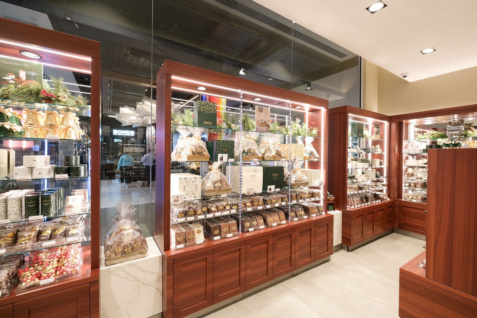 A well-lit gourmet shop with wooden display cases filled with chocolates and gifts.