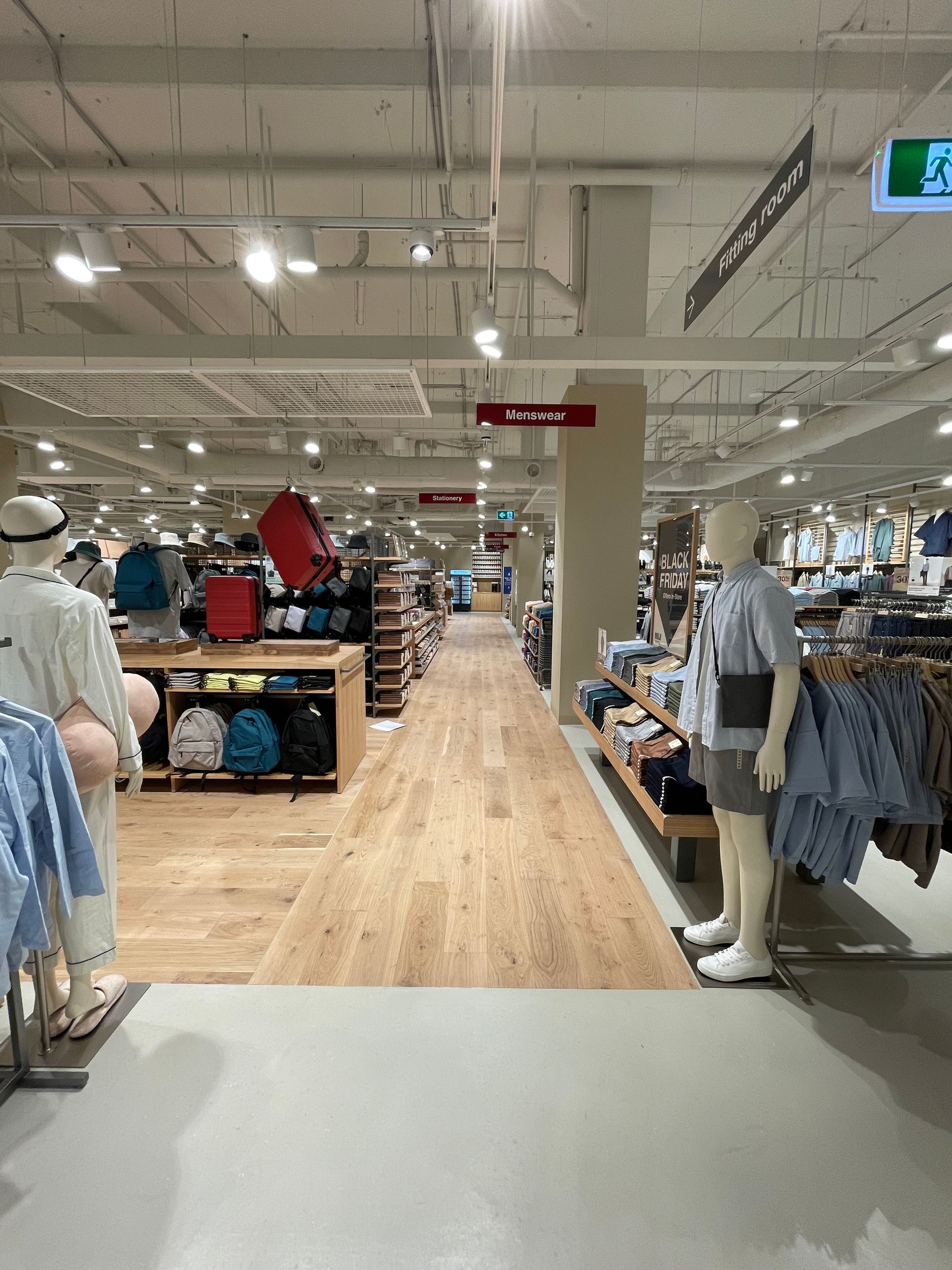 Clothing store interior with clothing racks and mannequins along aisles.
