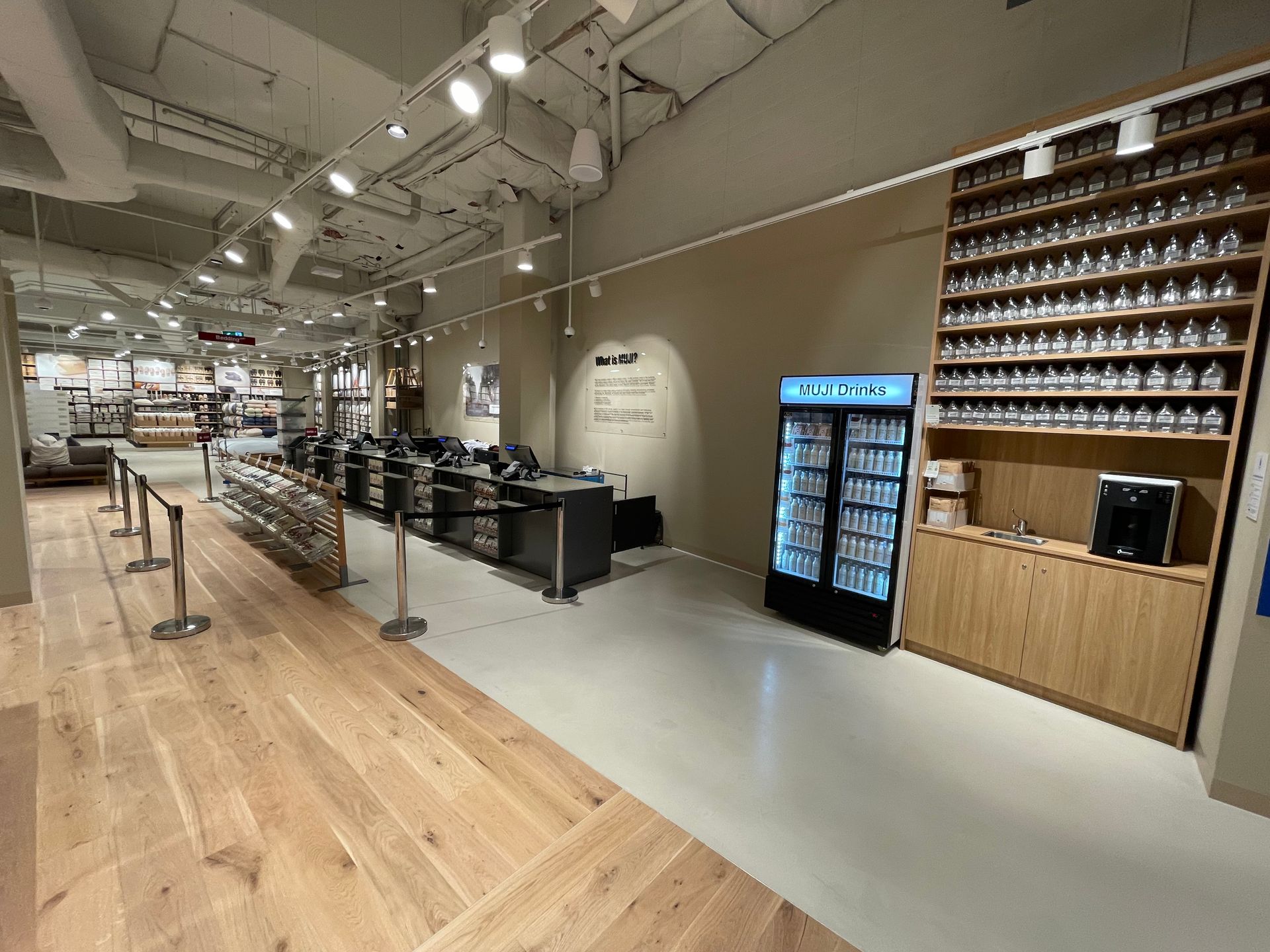 Interior of a store with wooden floors, displays, refrigerators, and a checkout area.