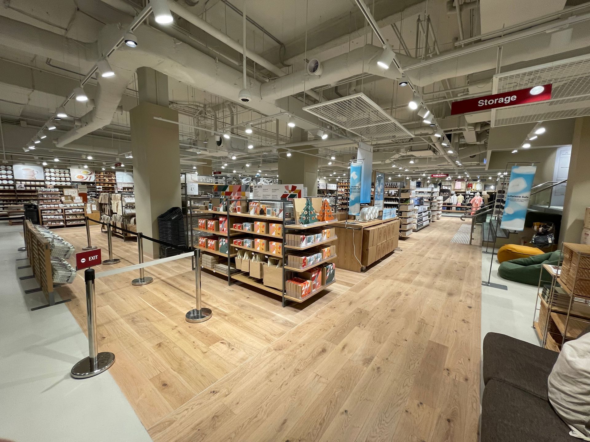 Interior view of a well-lit retail store with wood flooring and shelving filled with merchandise.