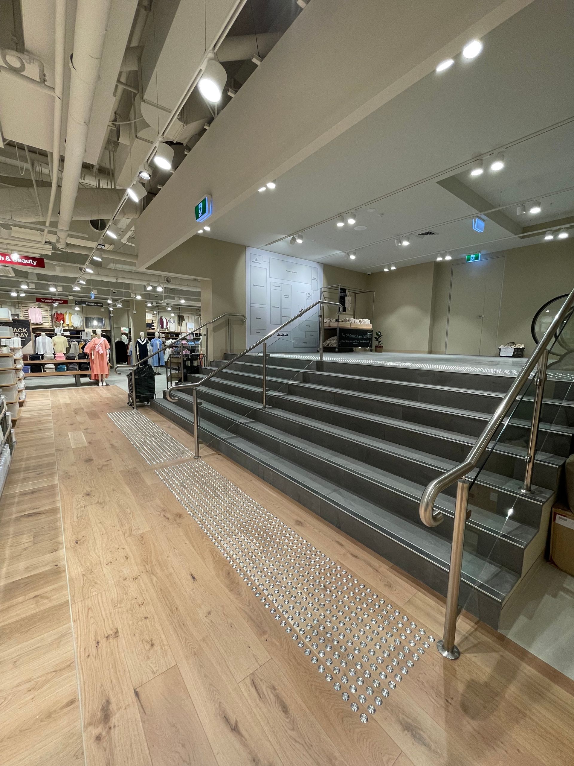 Interior view of a store with stairs, ramp, and customers browsing.