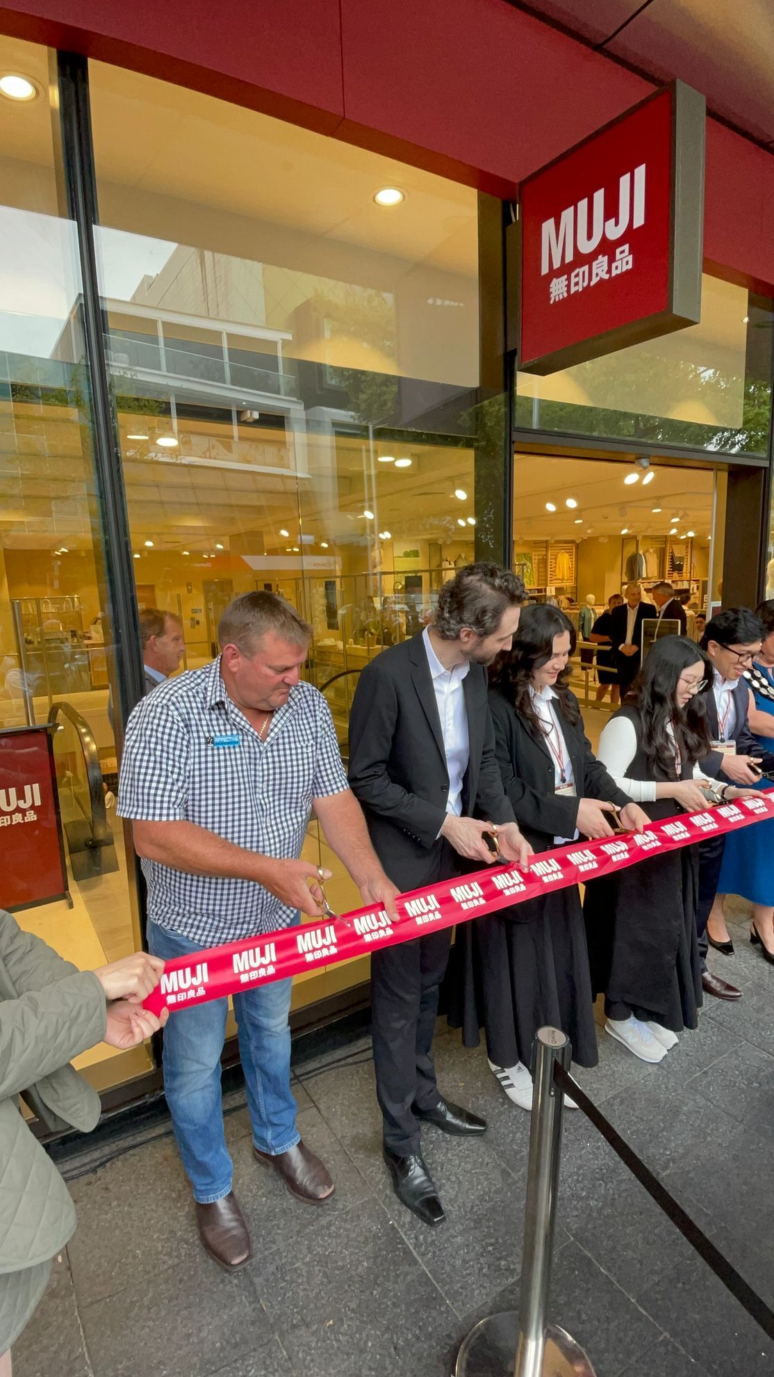 People cutting ribbon at the opening of a MUJI store.