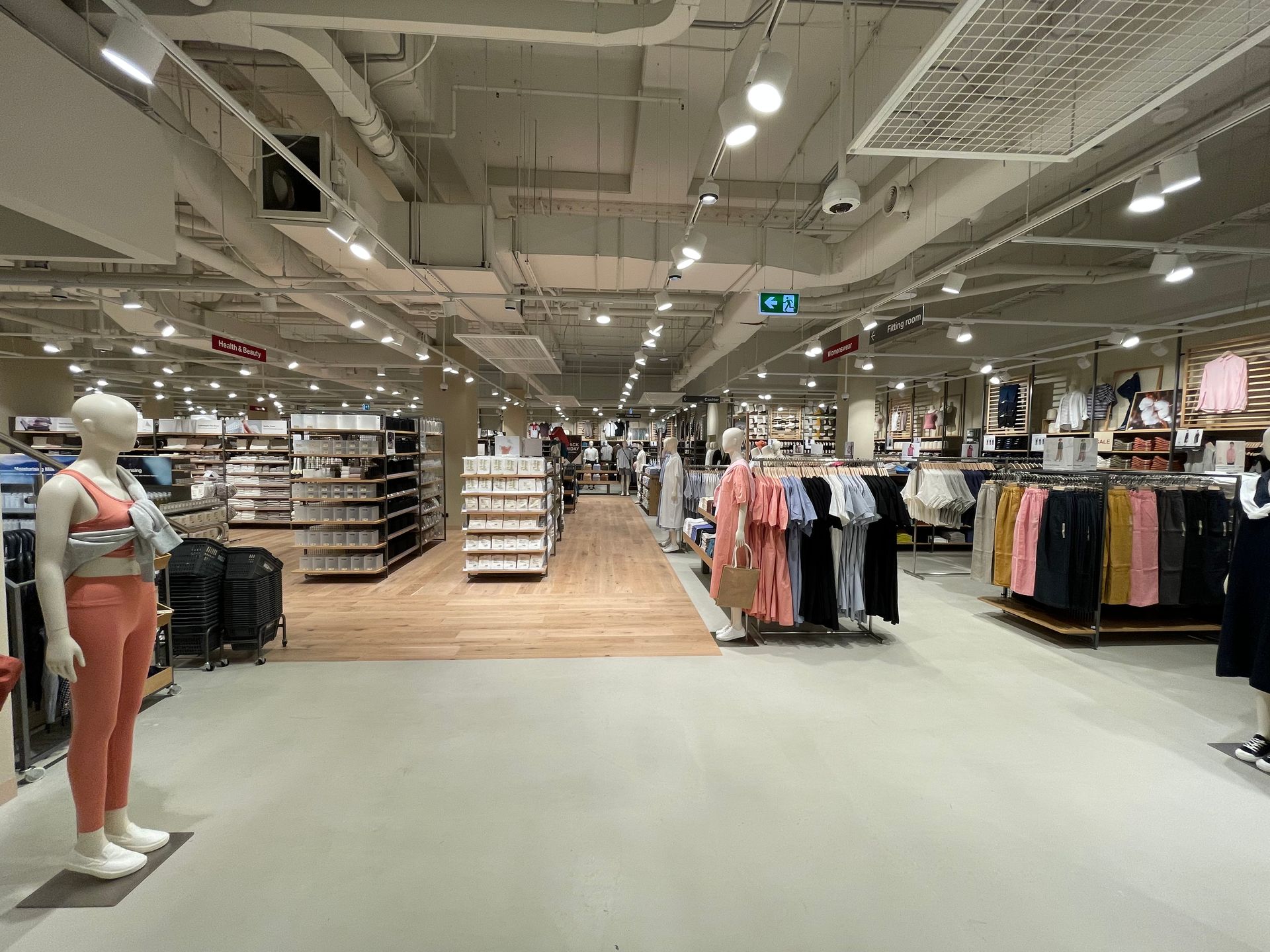 Clothing store interior, mannequins, clothing racks, and shelves of merchandise under bright lights.
