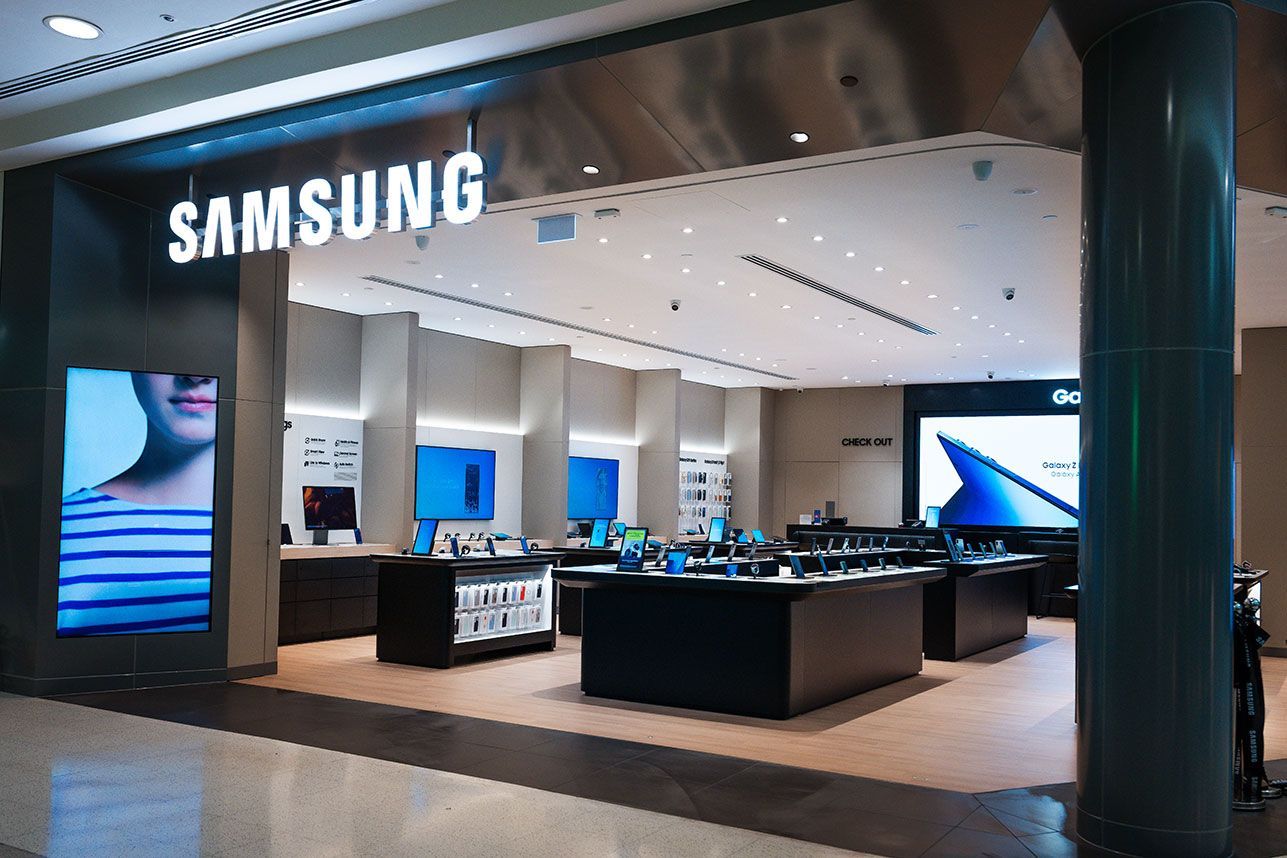 Samsung store front with large display showing a woman, inside a mall.
