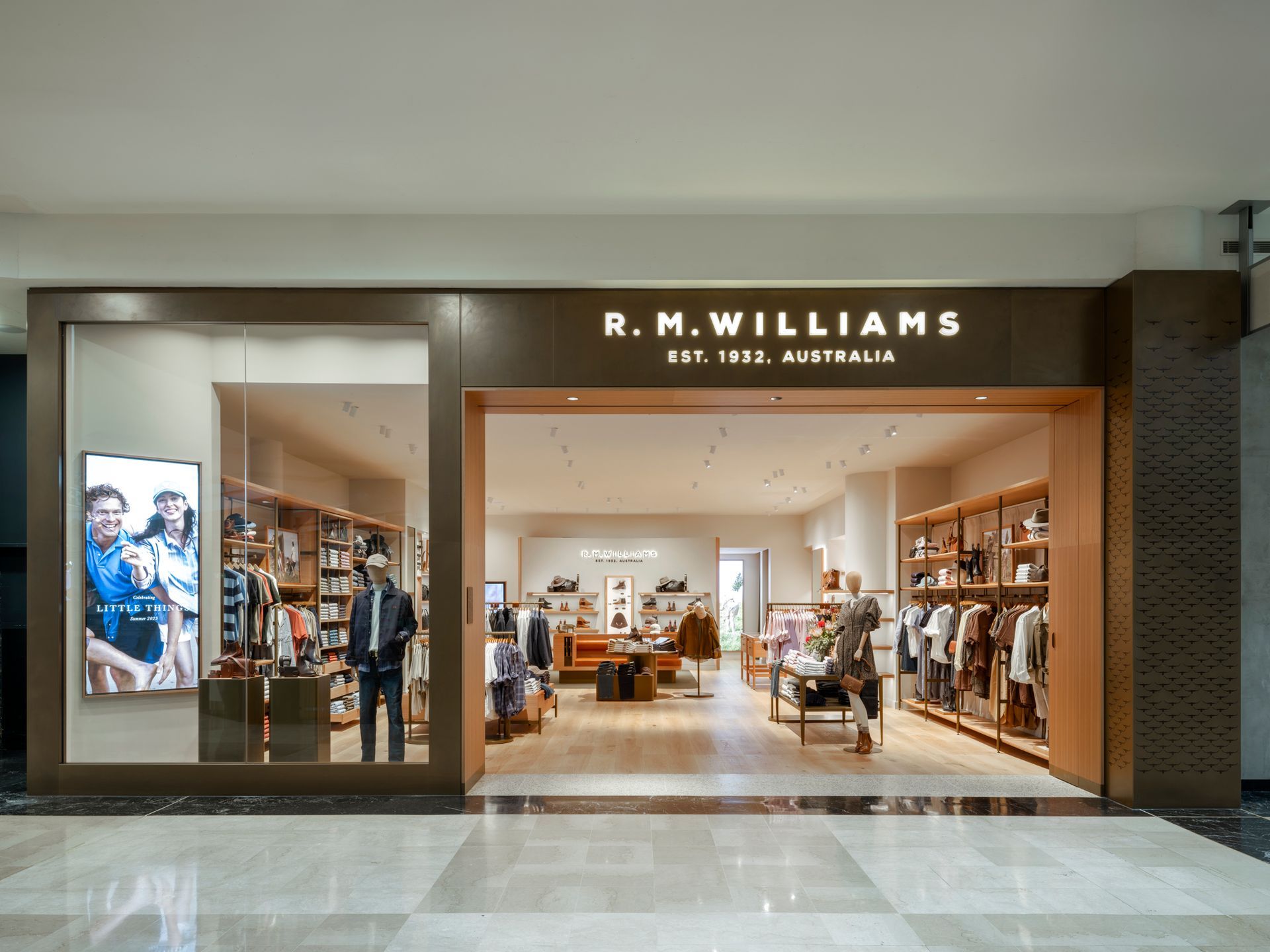 Display case of packaged chocolates inside a shop, with a window view of an outdoor urban courtyard.