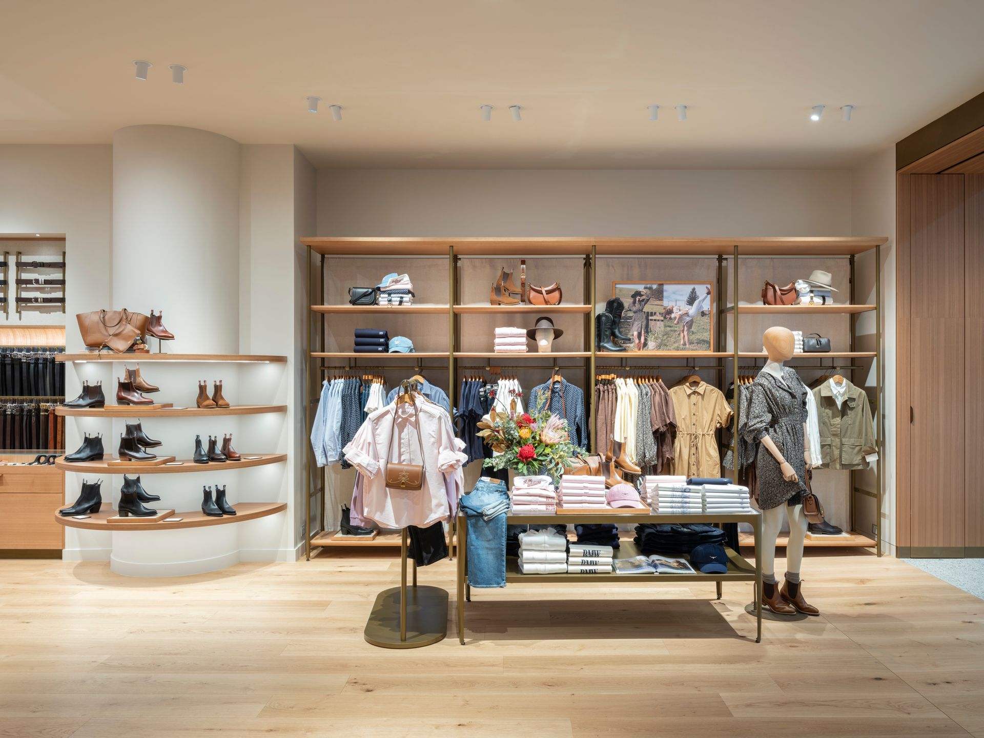 Clothing store interior with clothing racks, shelves, and a mannequin.