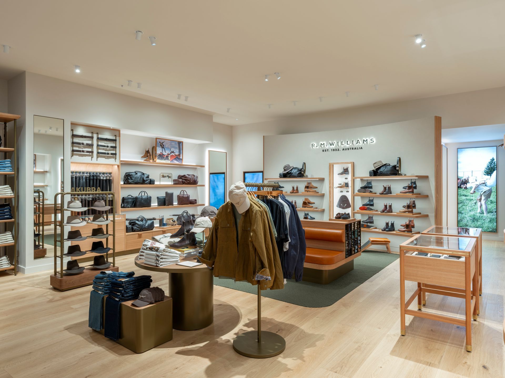 Interior of a stylish shoe and clothing store. Light wood floors, shelves displaying products, and a clothing rack with jackets.