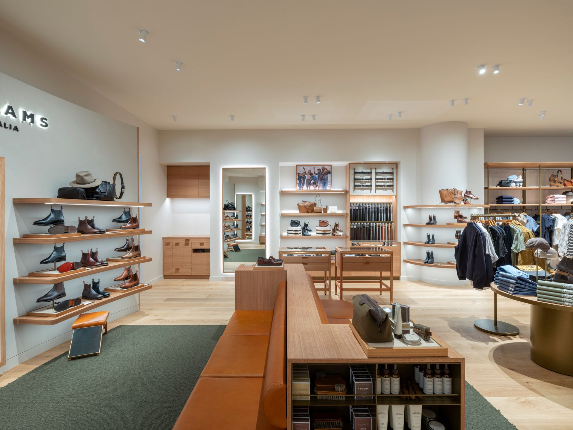Interior view of a shoe store with wooden shelves, shoes, clothes, and a seating area.