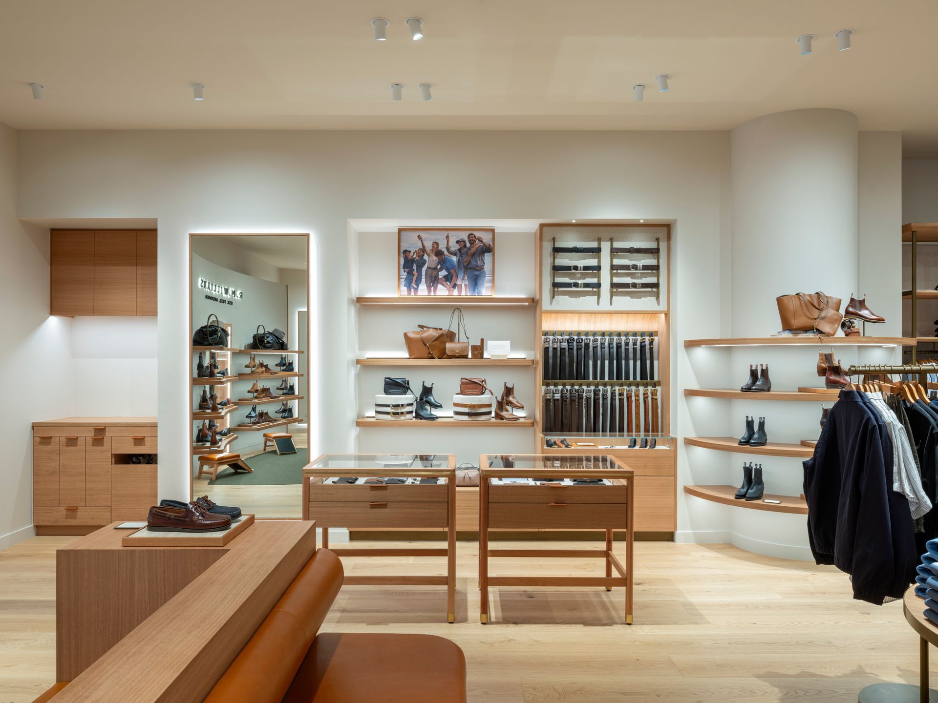 Interior of a shoe store with wooden shelves displaying various shoes, light-colored walls, and a wooden bench.