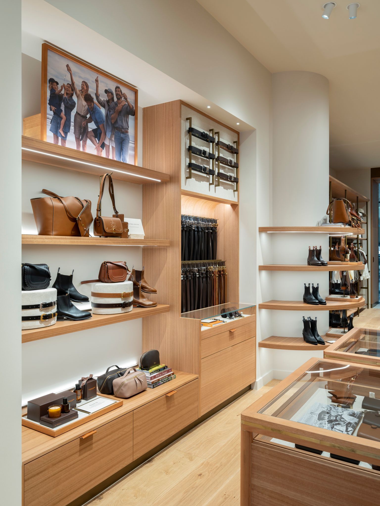 Interior view of a well-lit retail store with wooden shelves displaying leather goods.