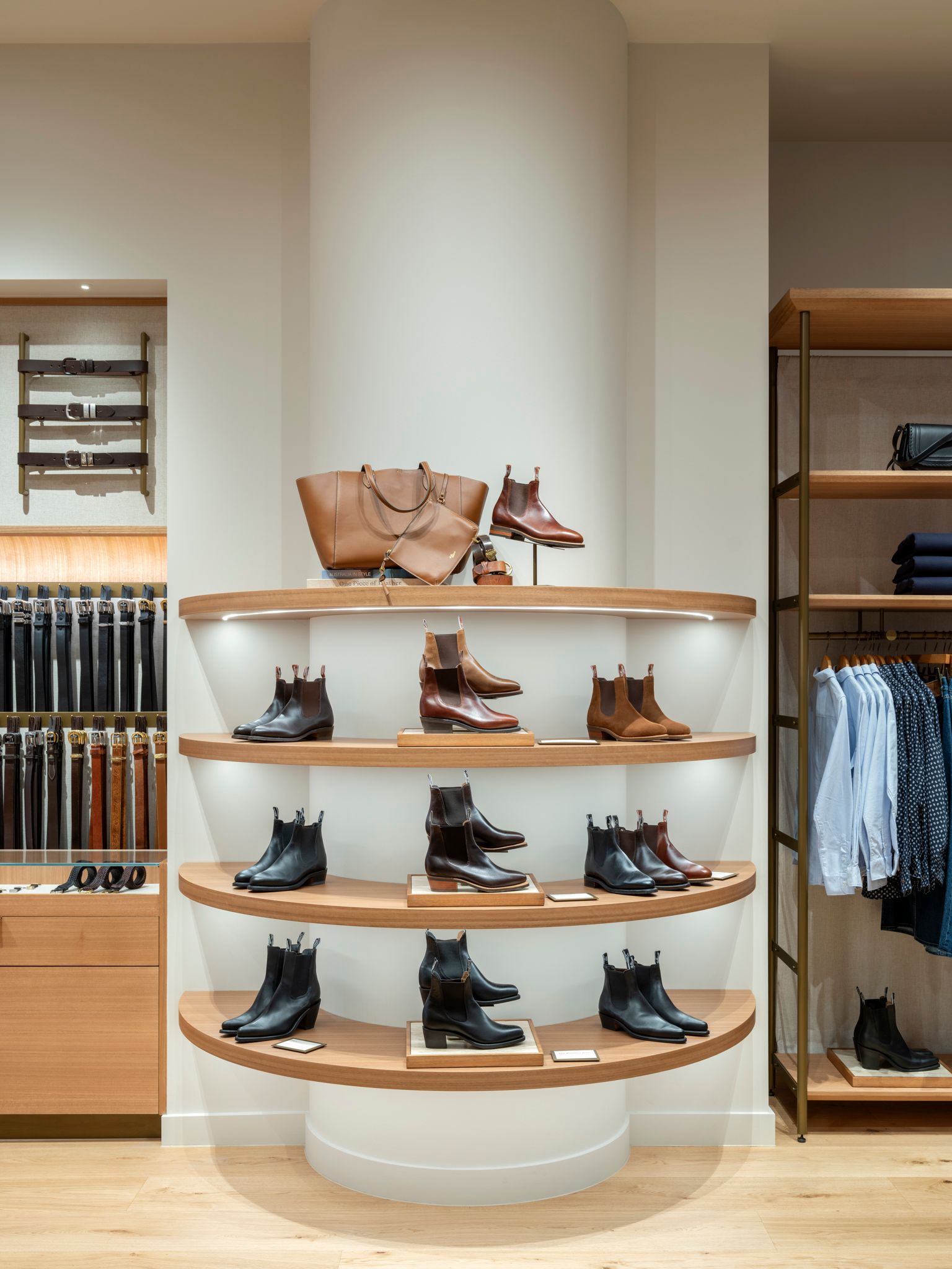 Interior shop display with boots and a handbag on wooden shelves.