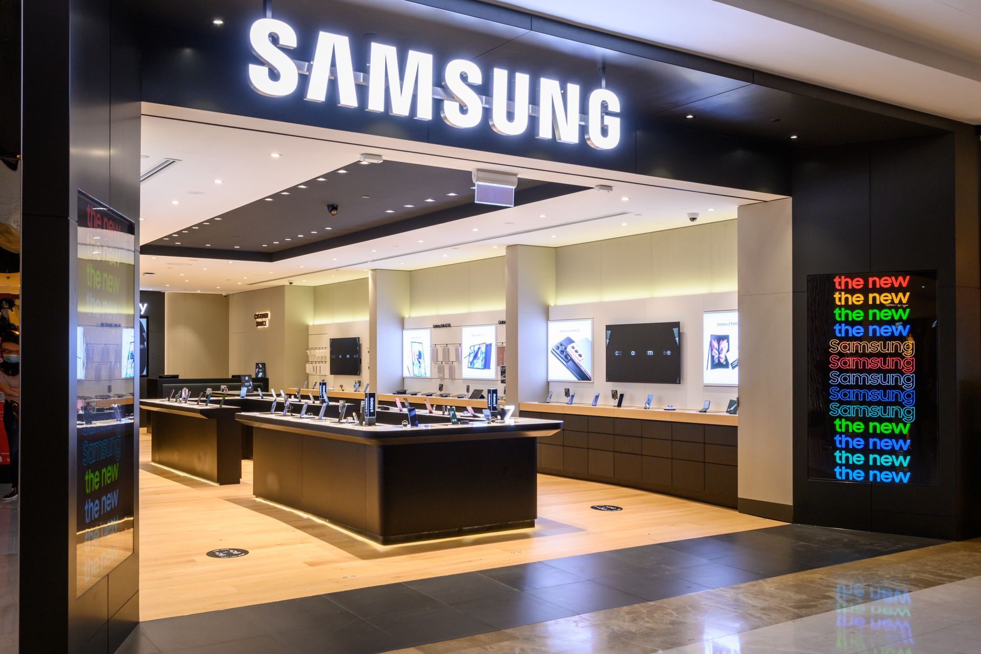 Samsung store entrance with illuminated sign and display tables.