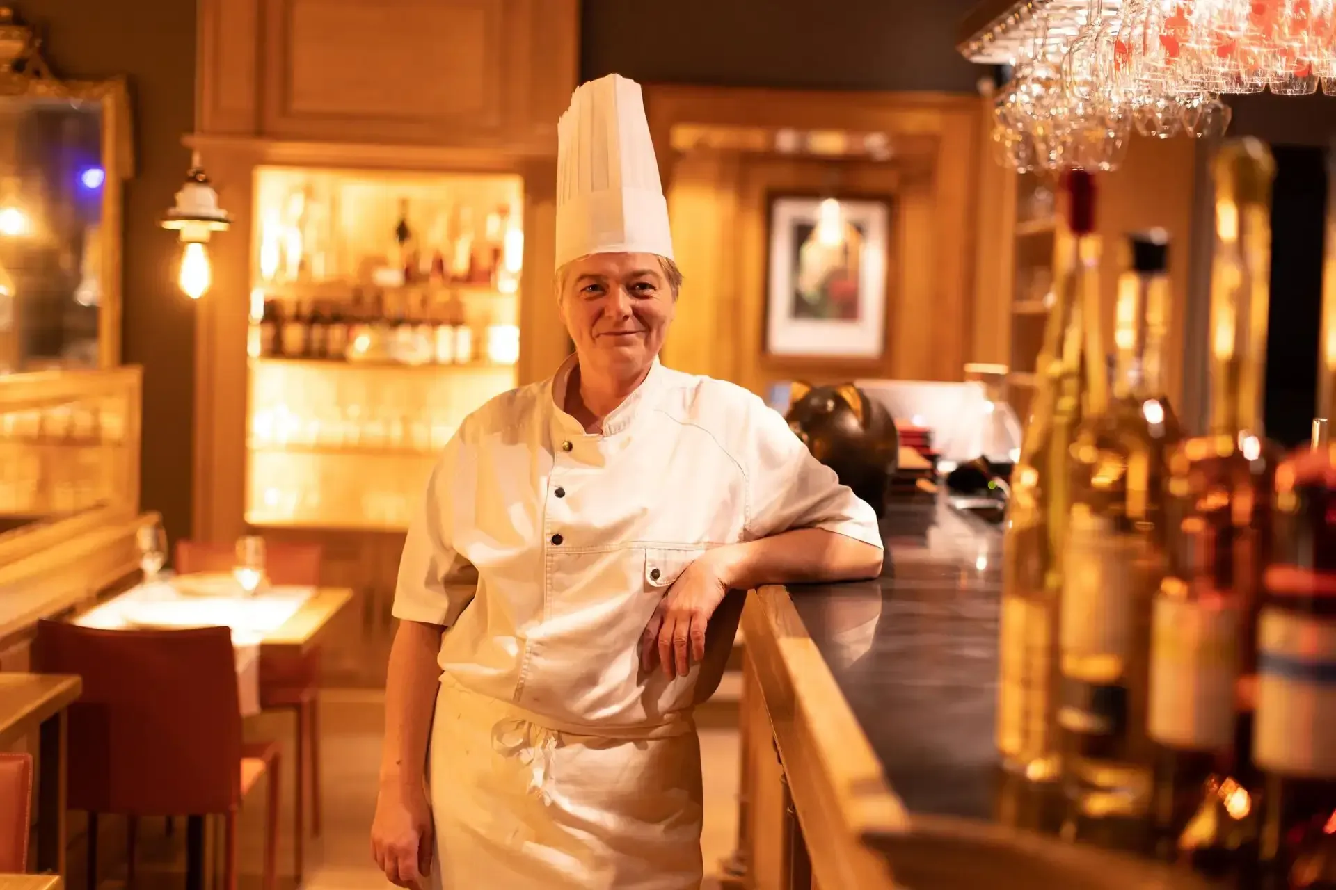 Un chef est adossé à un bar dans un restaurant.
