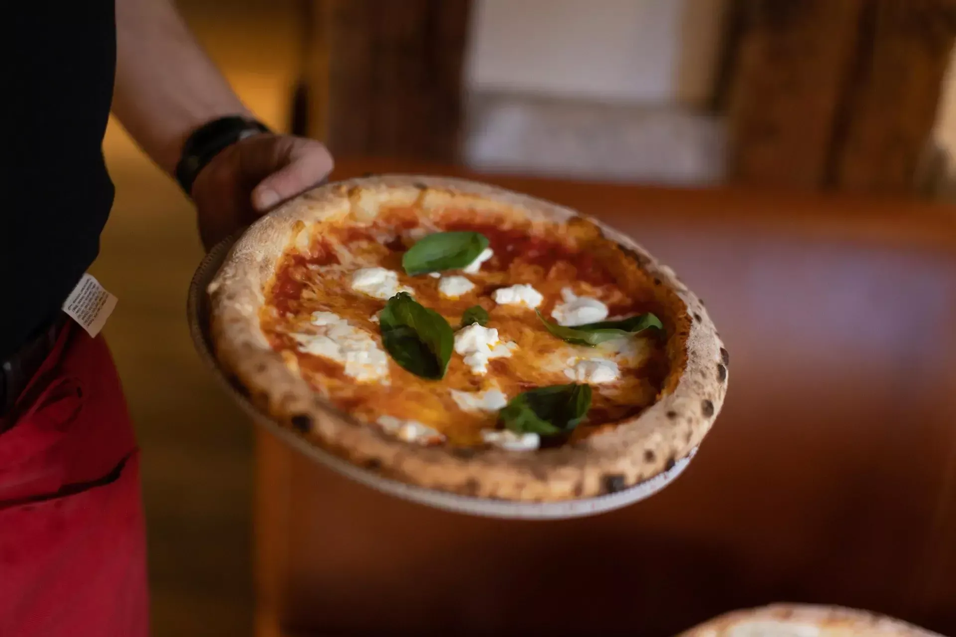 Une personne tient une pizza dans une assiette.