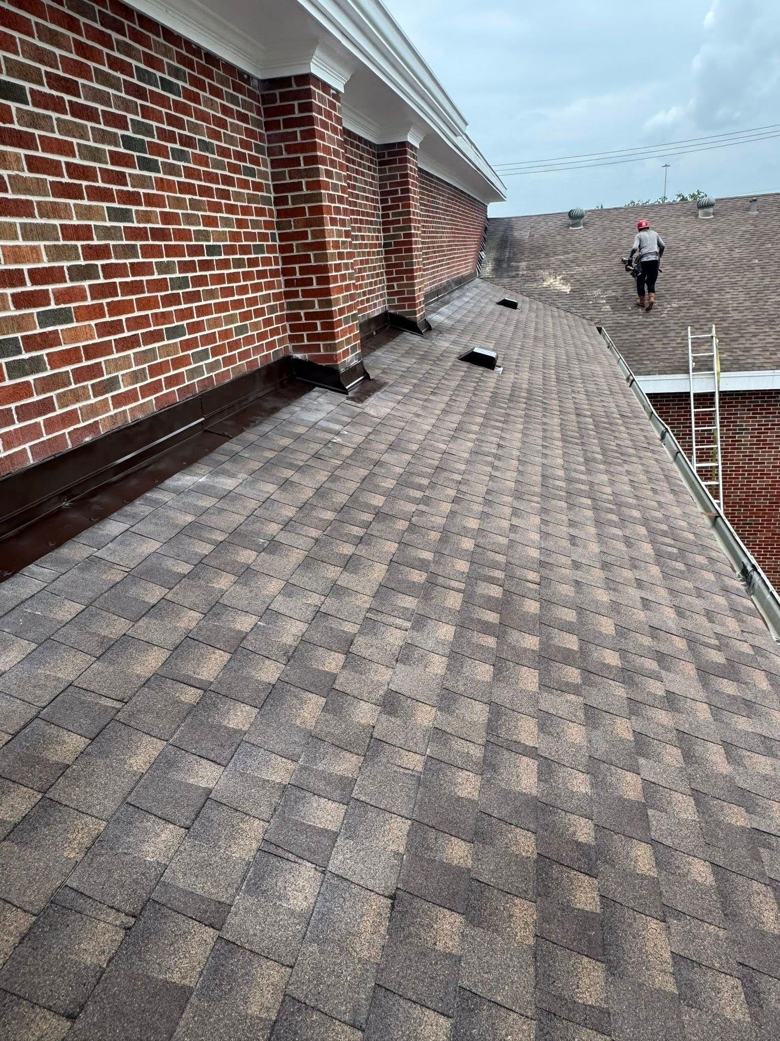 A man is standing on the roof of a brick building.