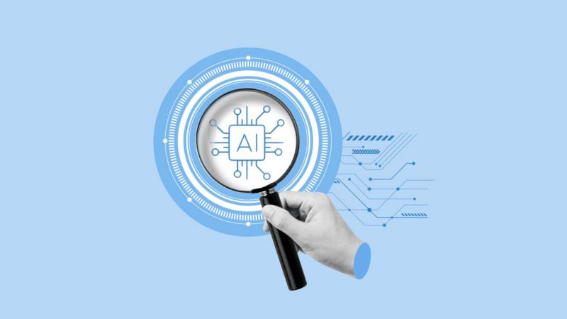 Hand holding magnifying glass over an AI chip design on a light blue background.