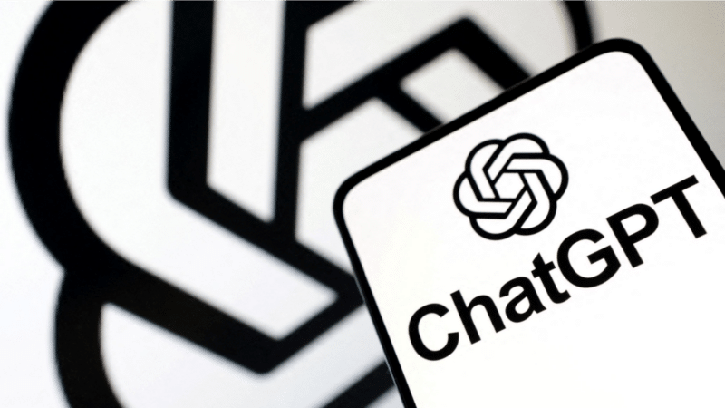 Black and white ChatGPT logo on a smartphone, with a blurred logo in the background.