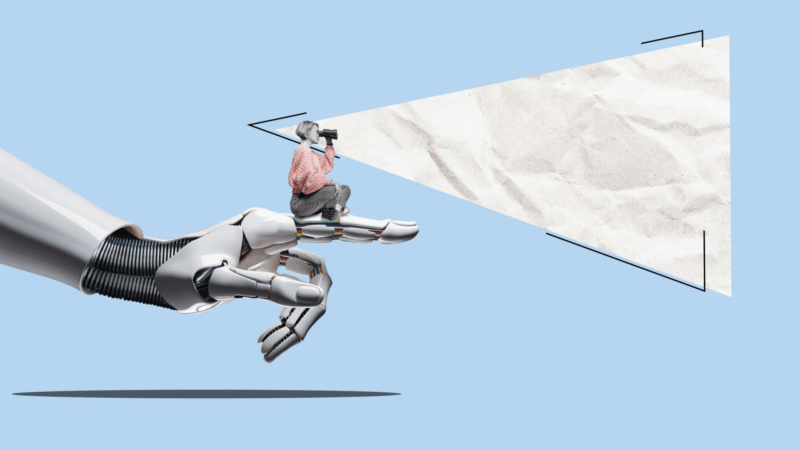 A robot hand holds a person taking a photo. A projected blank paper screen is ahead.