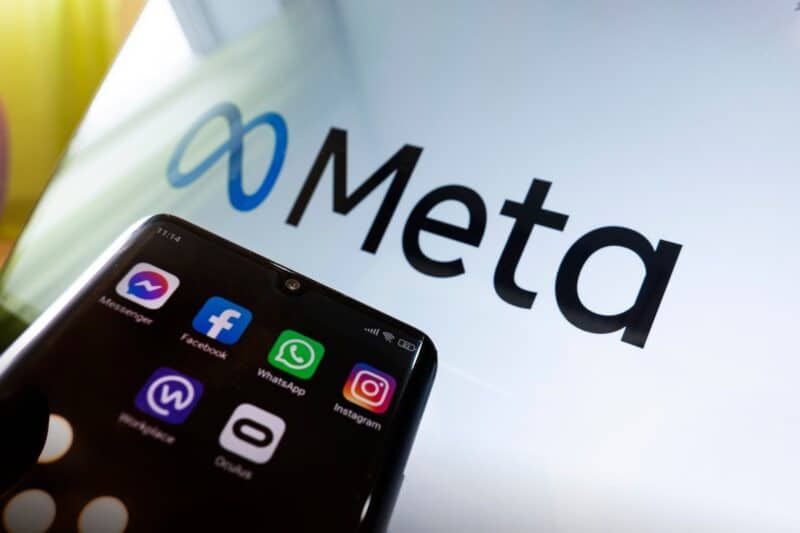 Smartphone displaying Meta's apps in front of the Meta logo.
