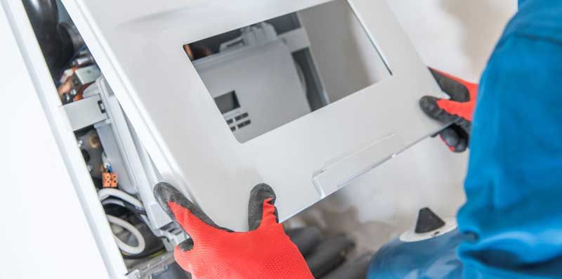 A man wearing red gloves is working on a boiler.