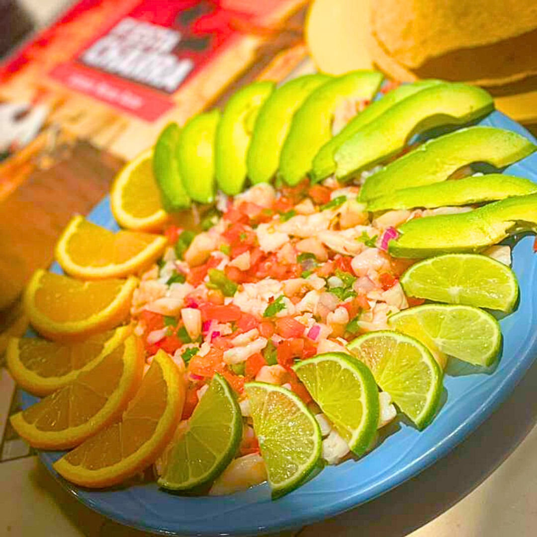 Plate of ceviche surrounded by orange, avocado, and lime slices.