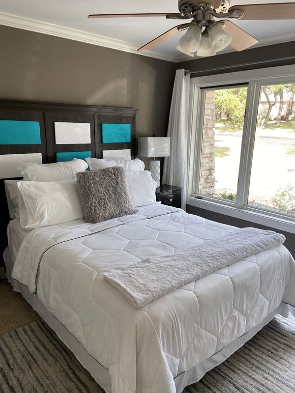 Bedroom with a bed, teal headboard, and a window with curtains.