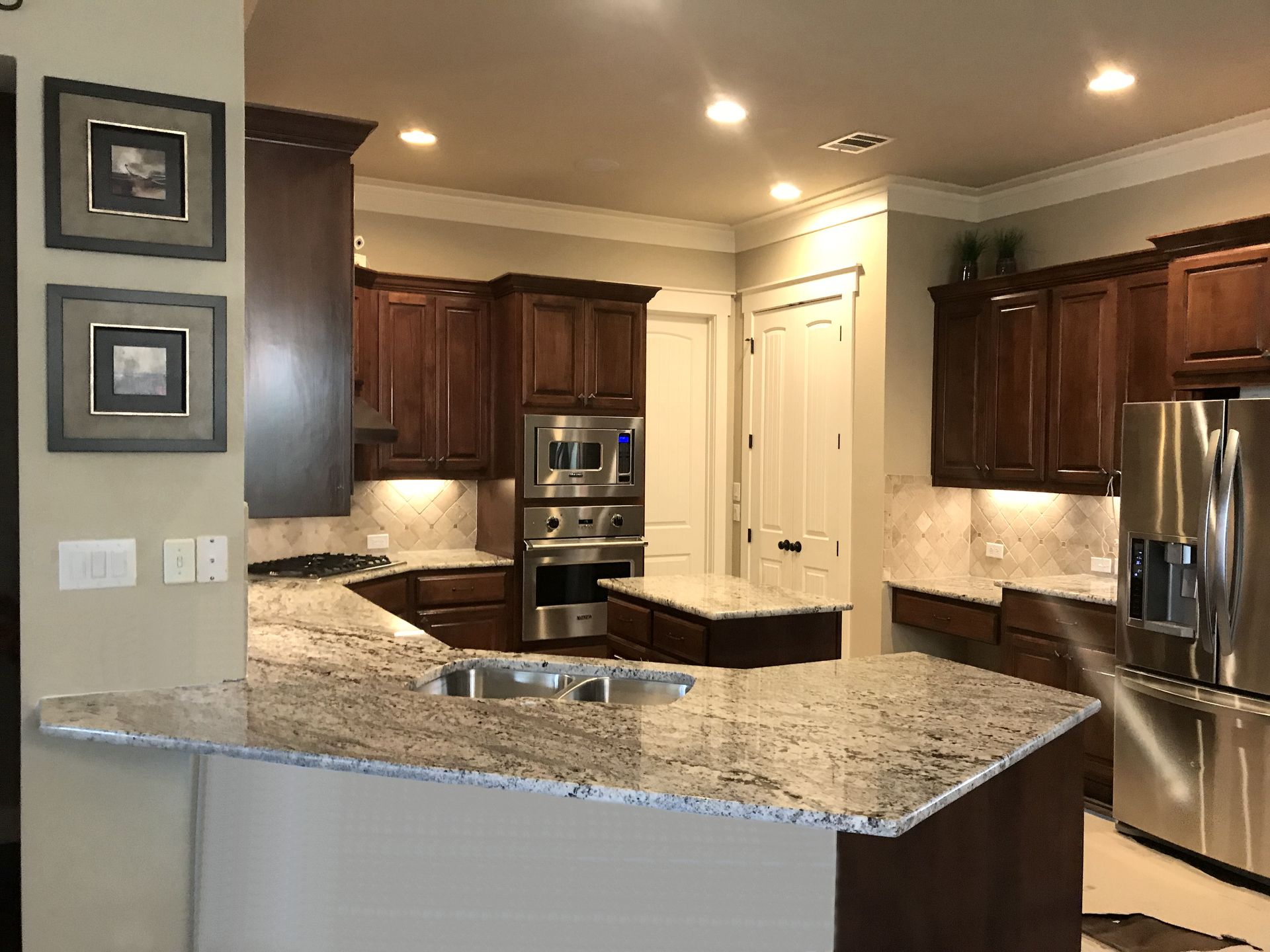 Kitchen with dark wood cabinets, granite countertops, stainless steel appliances, and a central island.