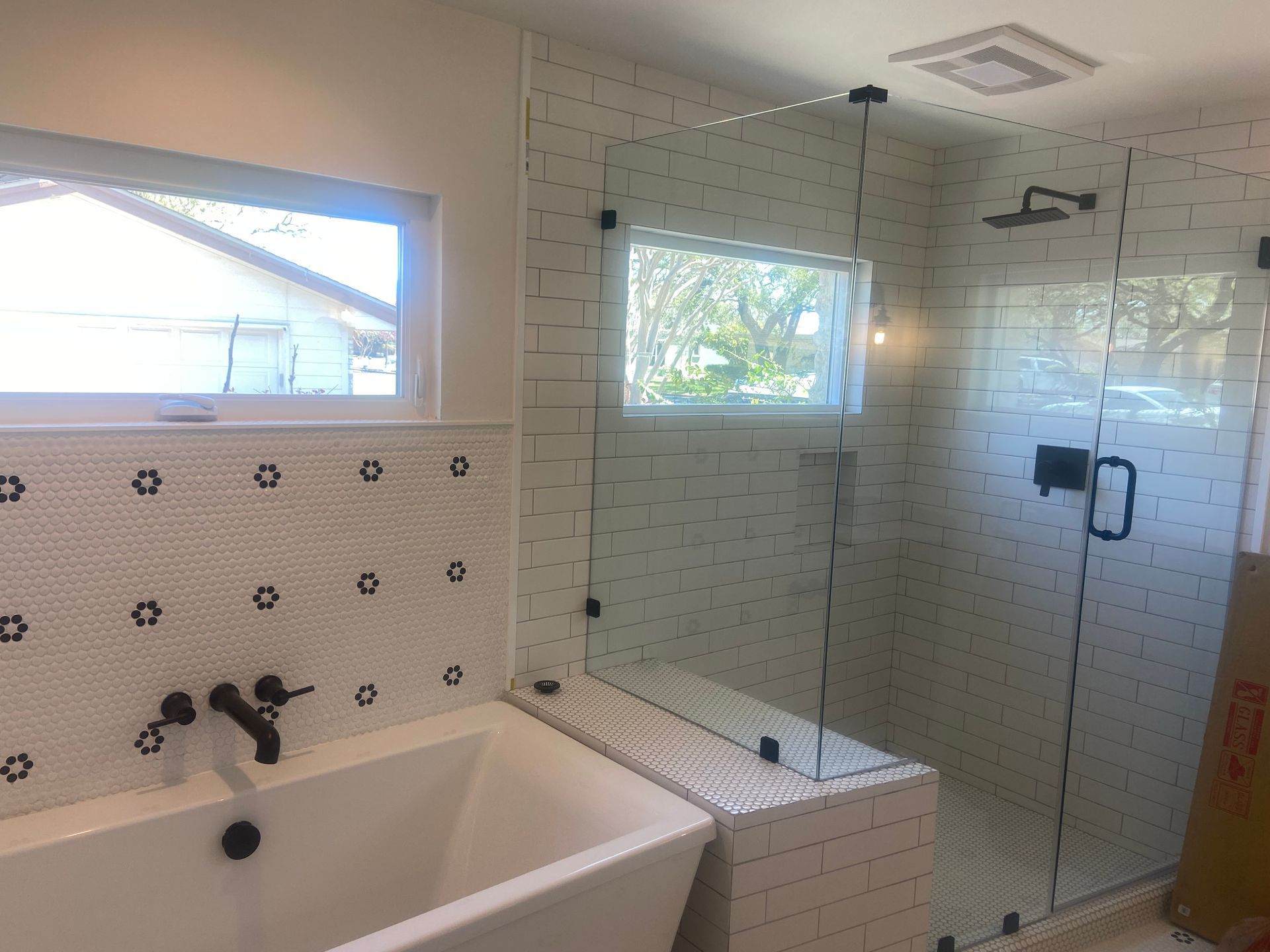 Modern bathroom with a white tub, shower, and black fixtures.
