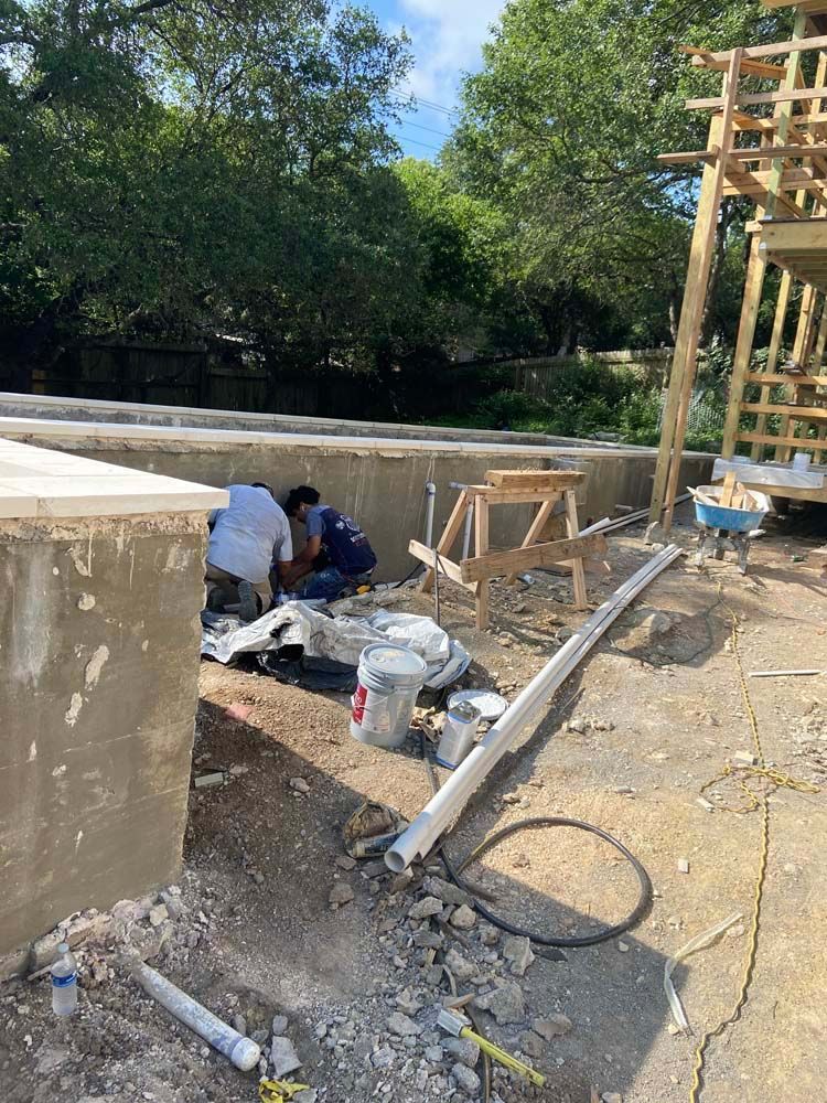 Construction workers near concrete structures outdoors, working with tools and materials.