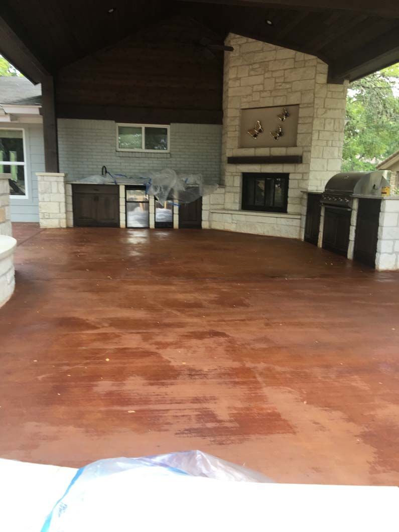 Outdoor patio with a brown concrete floor, kitchen, fireplace, and wood cabinets.