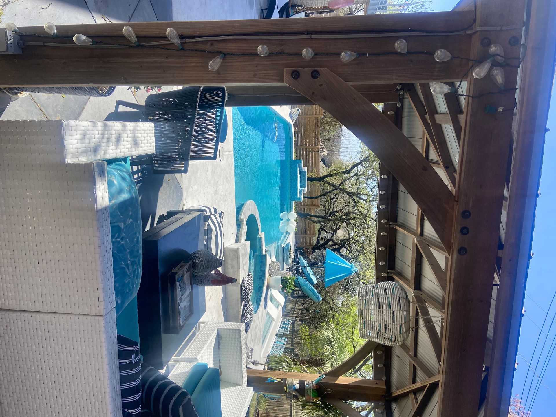 Wooden pergola frames a pool area with seating.