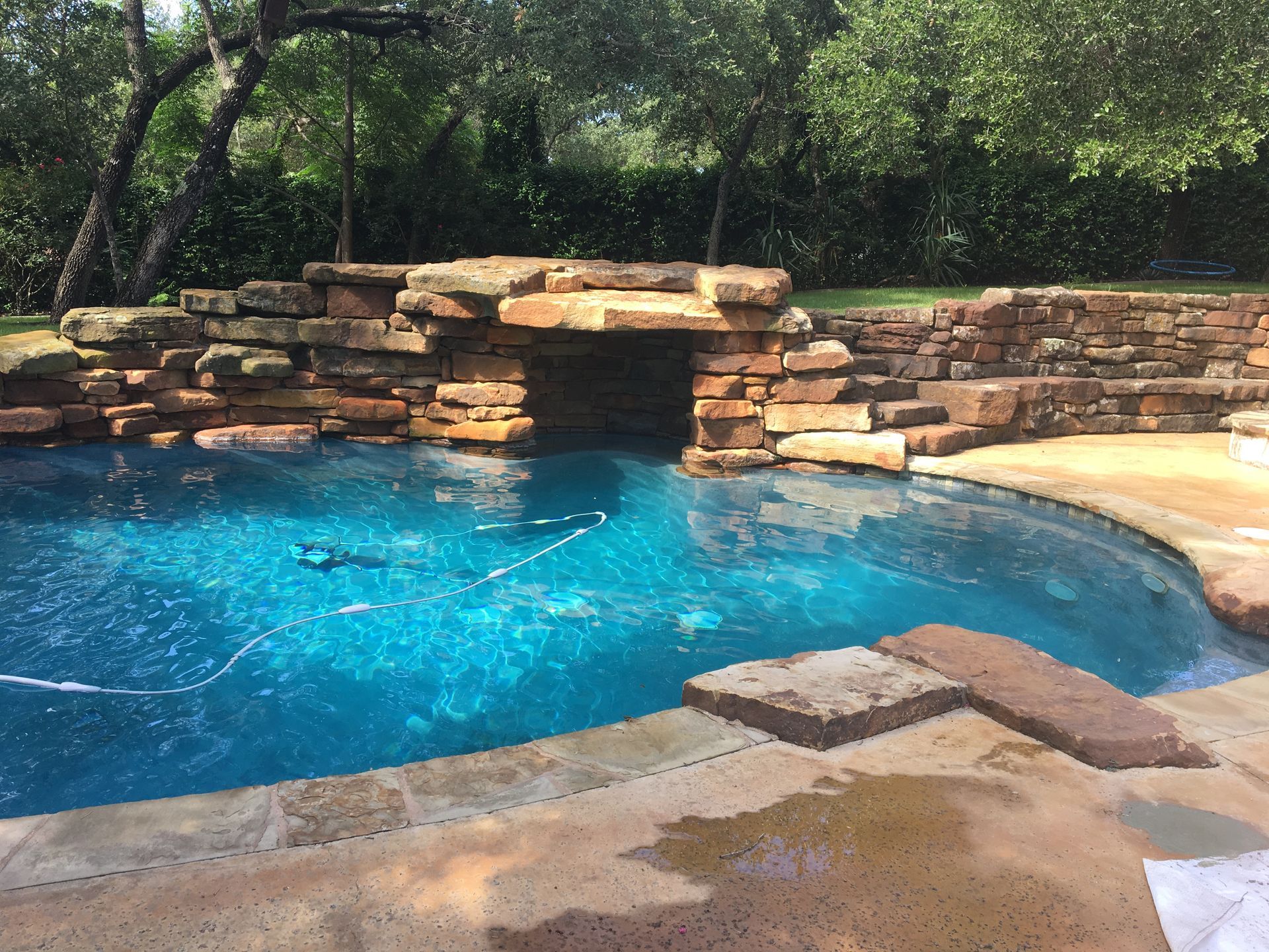 Pool with blue water, rock waterfall feature, and stone coping.