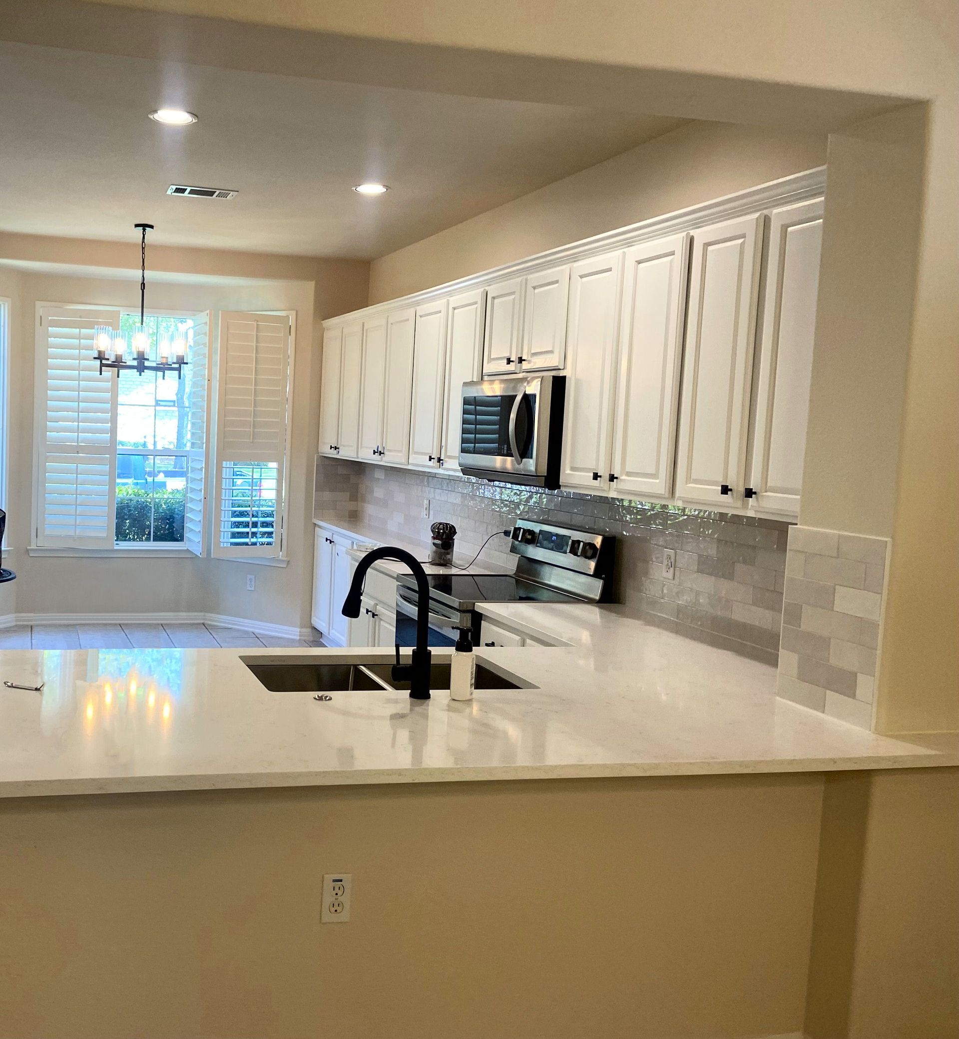 Kitchen with white cabinets, countertop, and sink. A window lets in natural light.