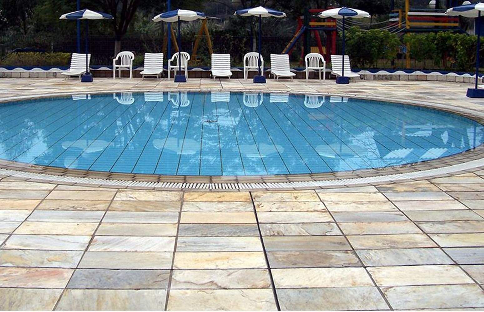 Swimming pool with blue water, lounge chairs, and umbrellas.