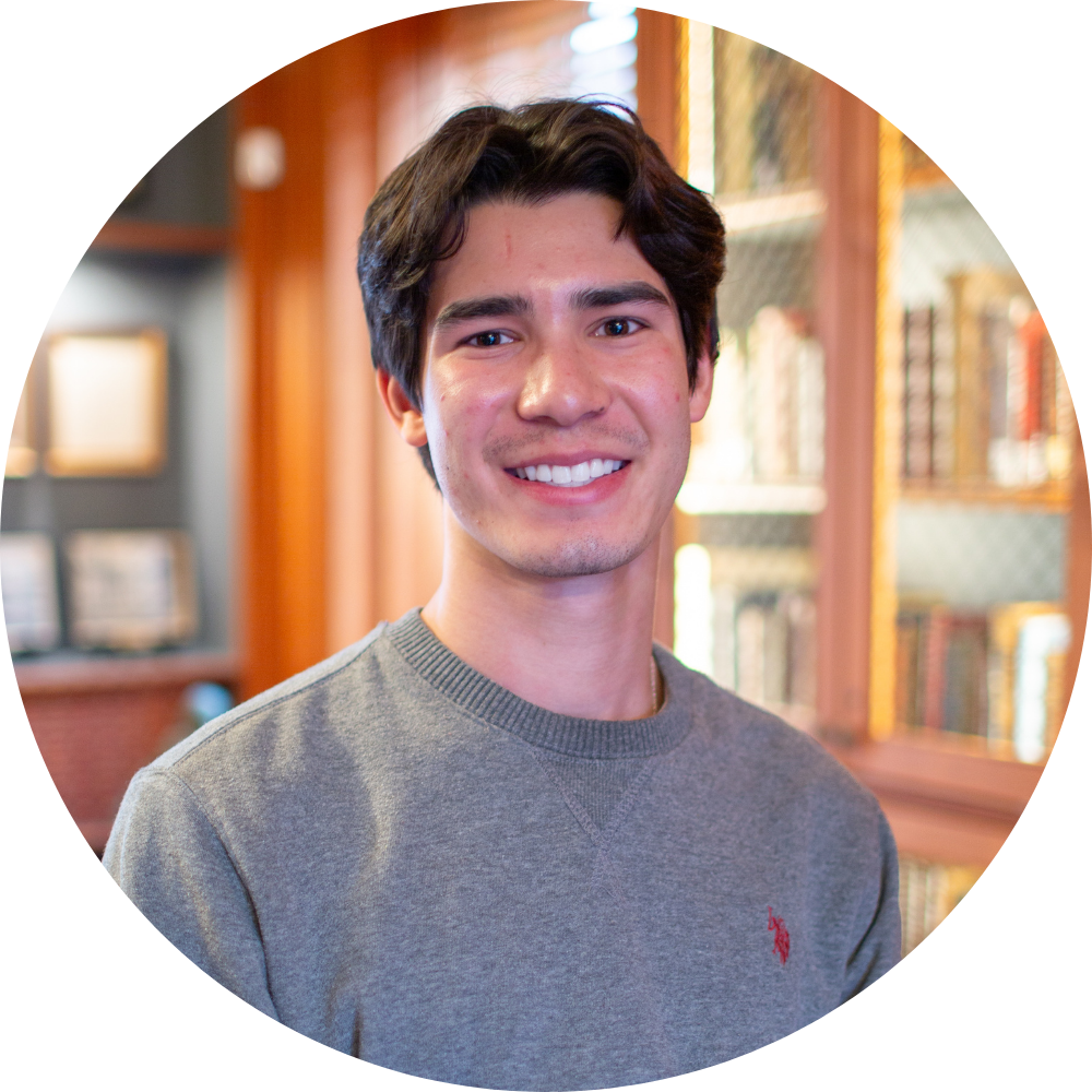 A woman wearing a black jacket and a gold necklace is smiling for the camera.