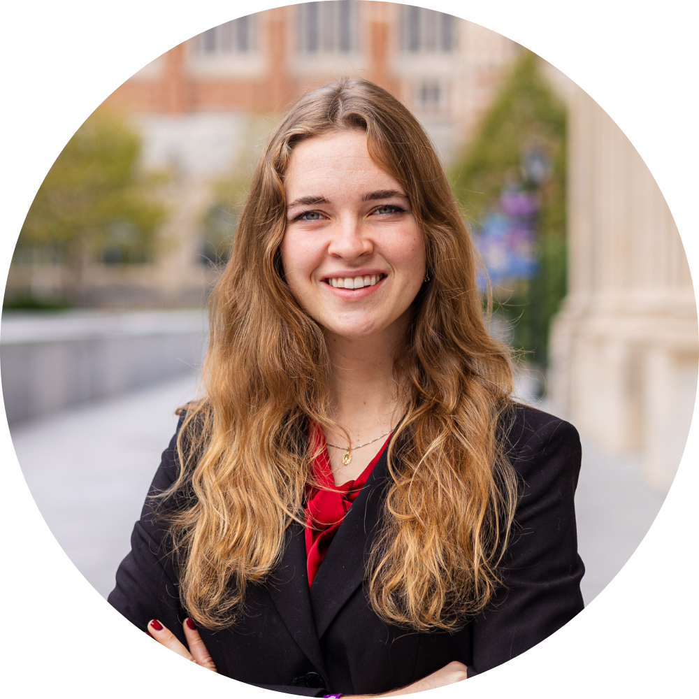A woman wearing a black jacket and a gold necklace is smiling for the camera.