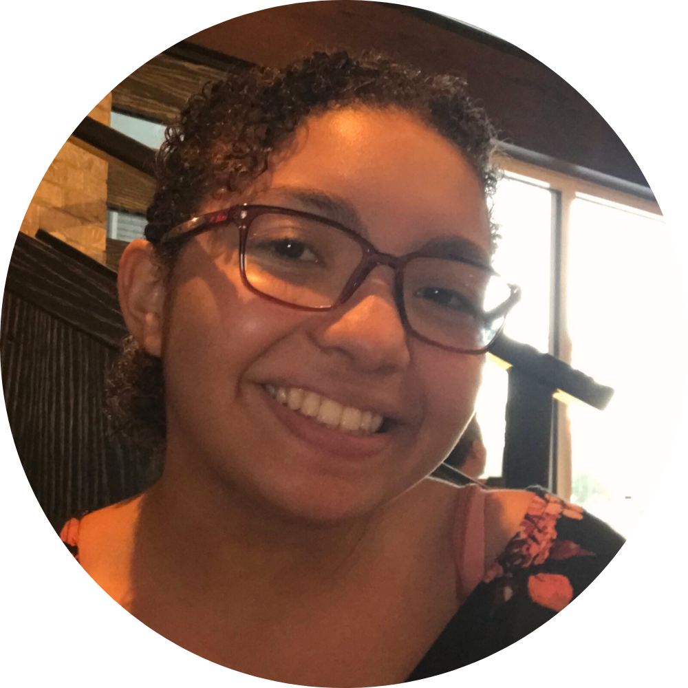 A woman wearing a black jacket and a gold necklace is smiling for the camera.