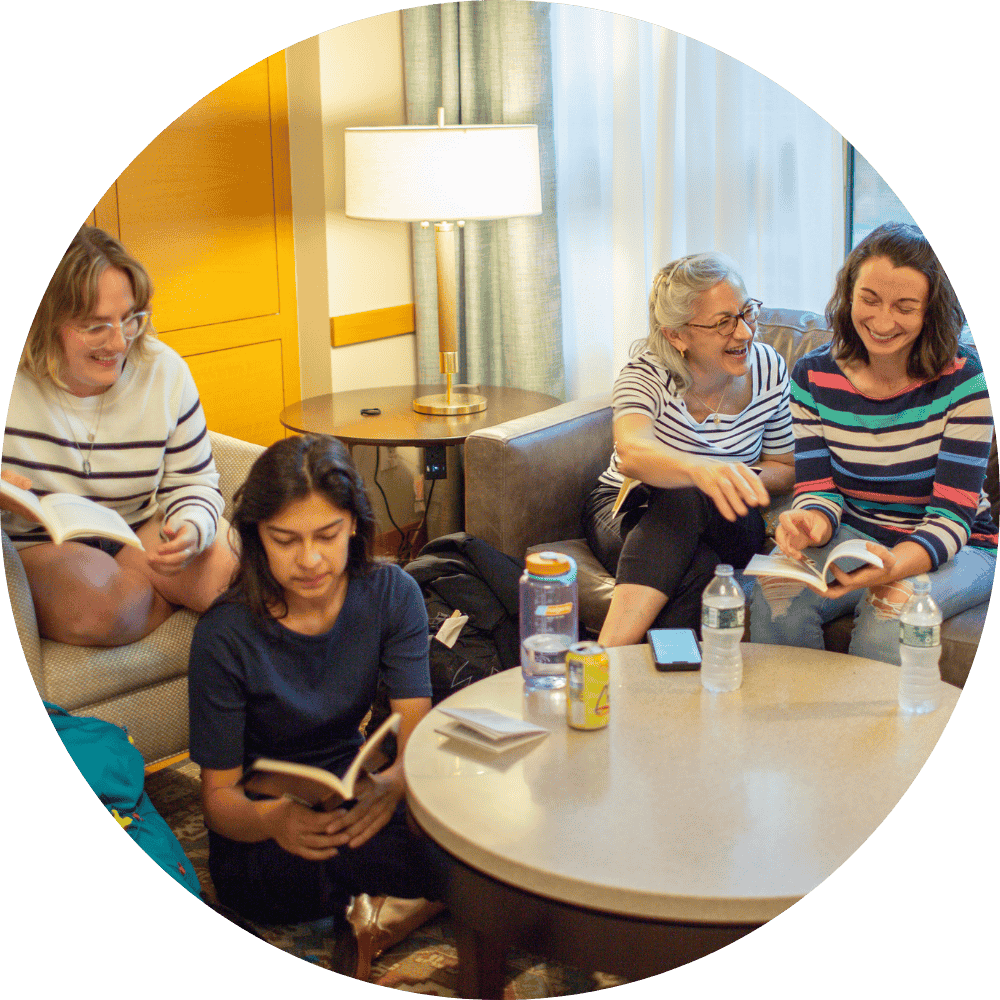 A group of women are sitting at a table reading books