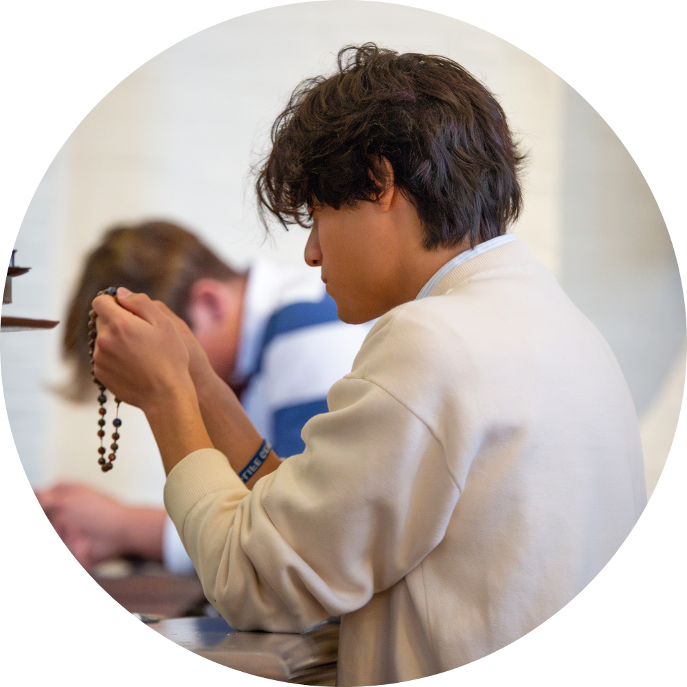 A man in a blue robe is holding a lit candle