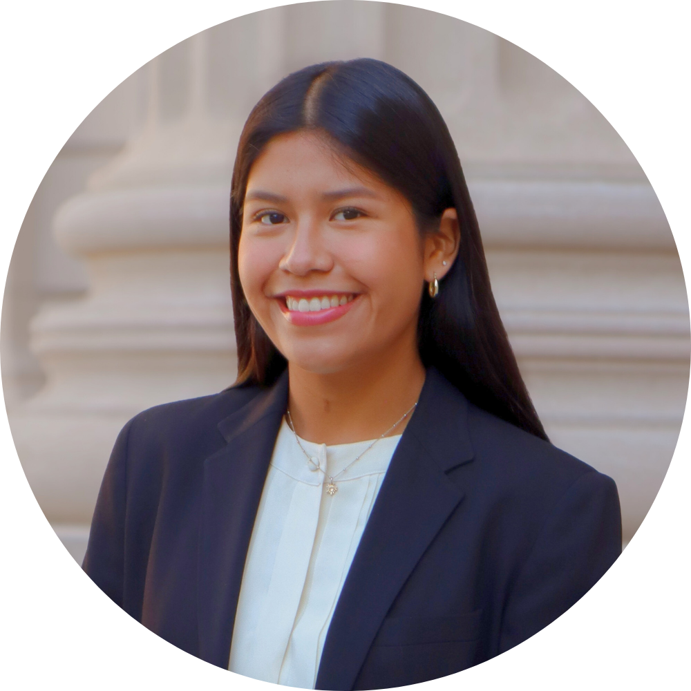 A woman is smiling for the camera while standing in front of a stone wall.