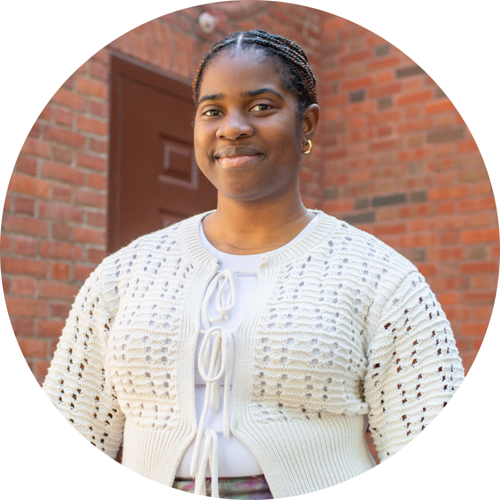 A woman wearing glasses and a necklace is smiling for the camera.