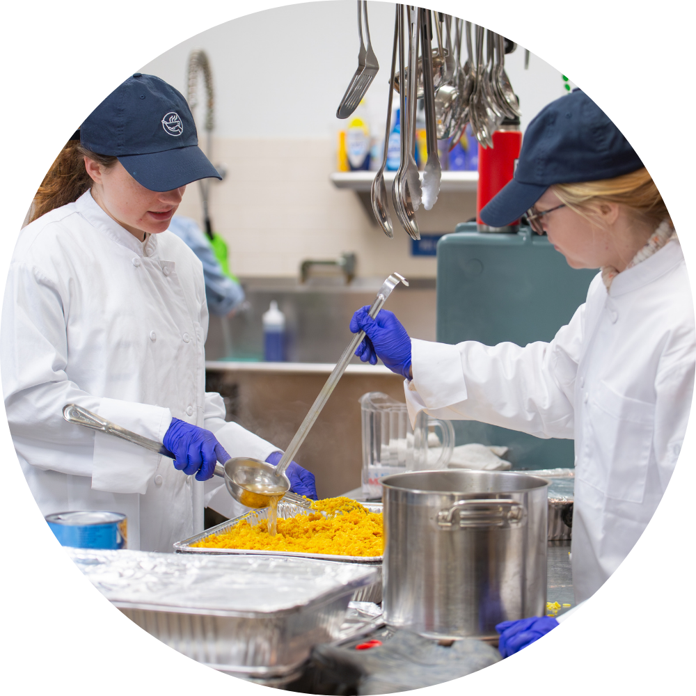Two soup kitchen volunteers preparing food.