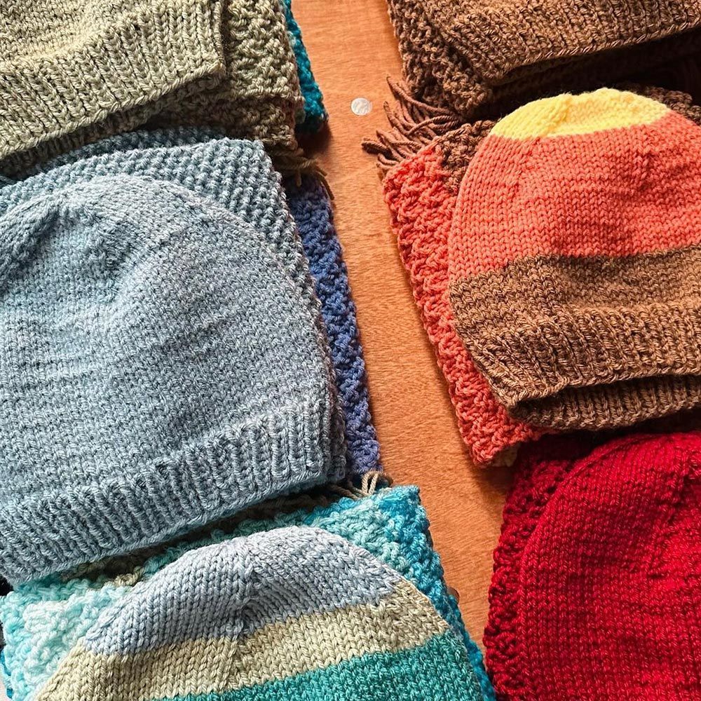 A bunch of knitted hats are stacked on top of each other on a table.