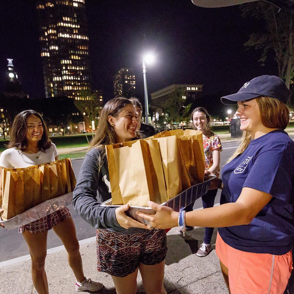 A woman in a blue shirt is giving a brown bag to another woman