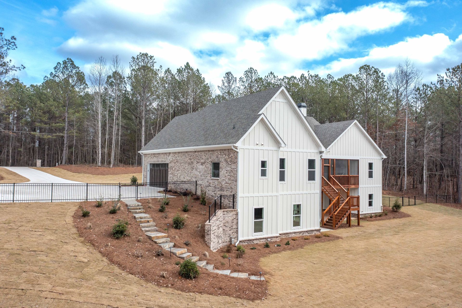 A large white house is sitting on top of a hill in the middle of a forest.