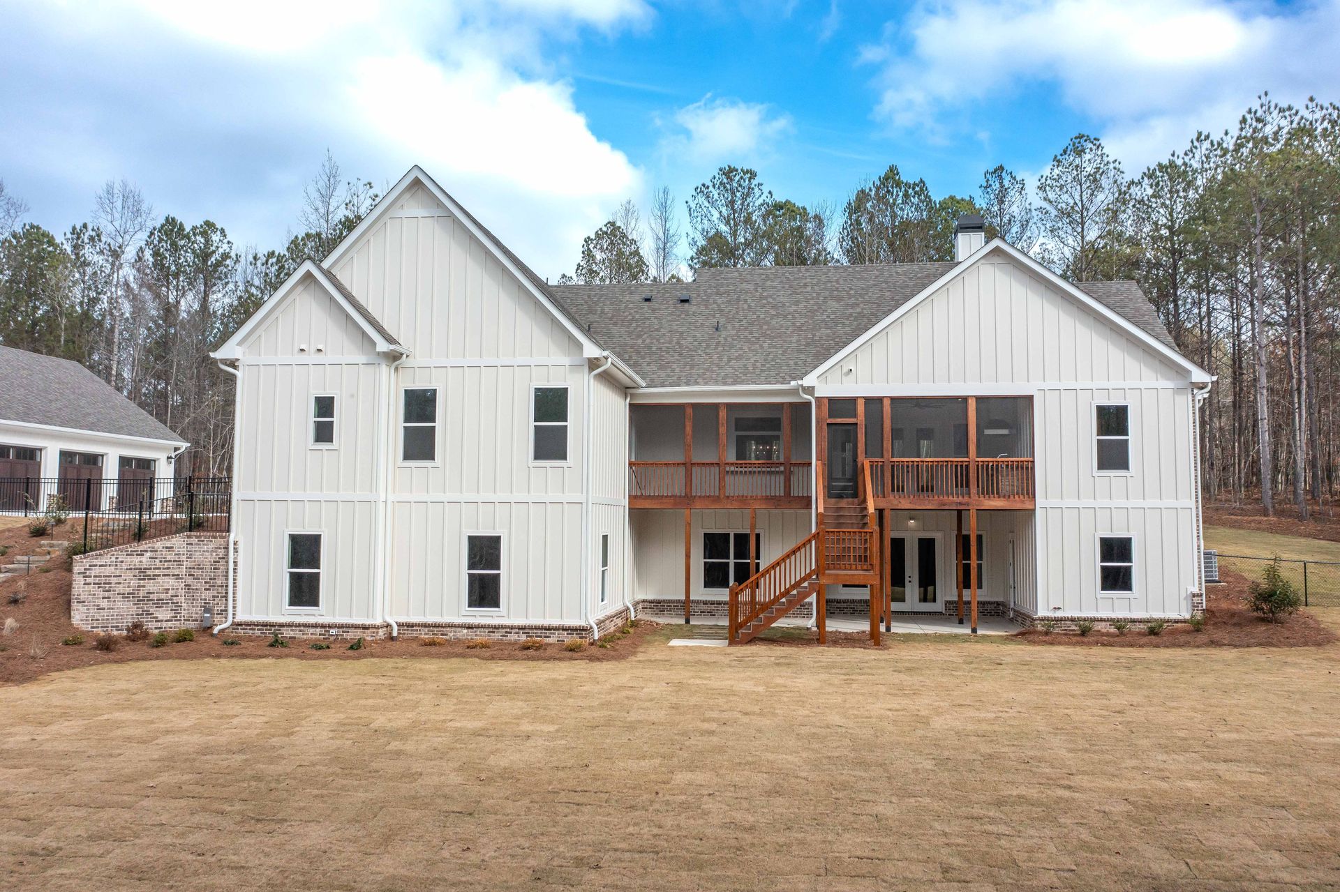 The back of a large white house with a large screened in porch.
